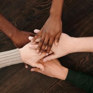 A diverse group of hands joining together, symbolizing unity and teamwork on a wooden surface.